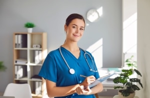 Happy nurse smiling as she writes on a clipboard